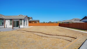 Ein Wohngrundstück mit einem Haus, einem Holzzaun und einem wolkenlosen Himmel.