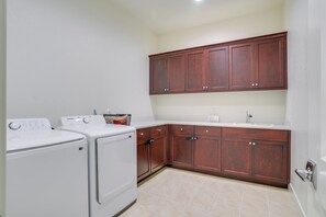 A laundry area with two washing machines, wooden cabinets, and a countertop. - Private Yard & Patio! Modern Manteca Gem (Manteca)
