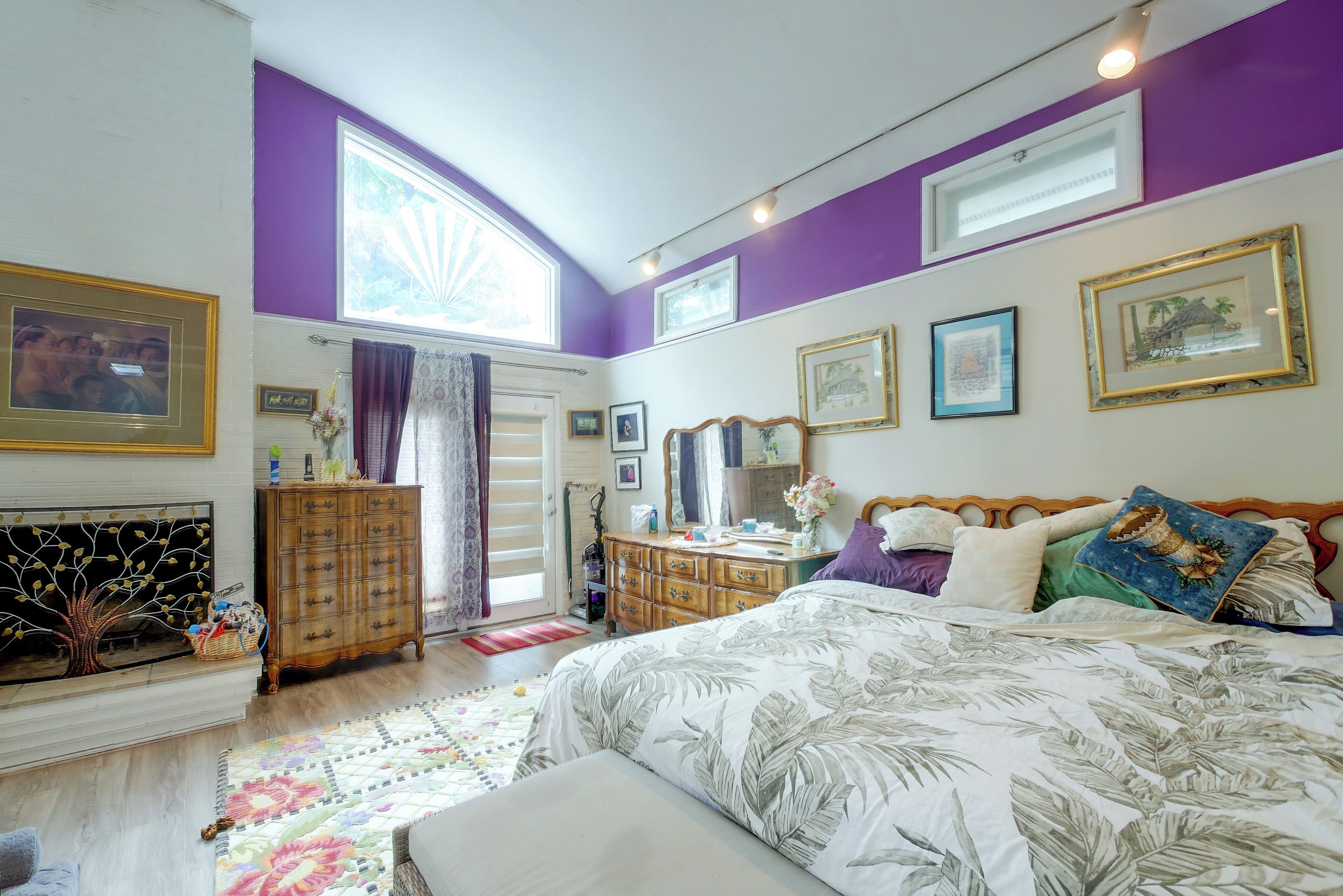 A bedroom with a bed, dresser, and a window with curtains.