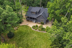 A two-story house with a dark roof, surrounded by dense forest. - Views, Hot Tub & Fire Pit! Luxe Blue Ridge Retreat (Blowing Rock)