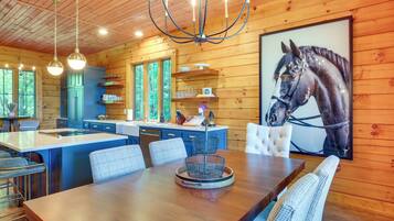 A wooden cabin interior with a dining area, kitchen, and a large horse portrait on the wall.