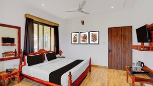 A hotel room with a wooden bed, a ceiling fan, a TV, and framed artwork on the wall. - Collection O RTO Office Udaipur (Udaipur)