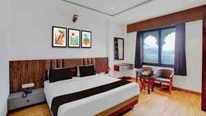 A modern hotel room with a large bed, a desk, a chair, and artwork on the wall. - Collection O RTO Office Udaipur (Udaipur)