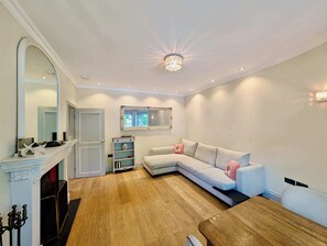 Una sala de estar moderna con un sofá modular, una chimenea y una araña.