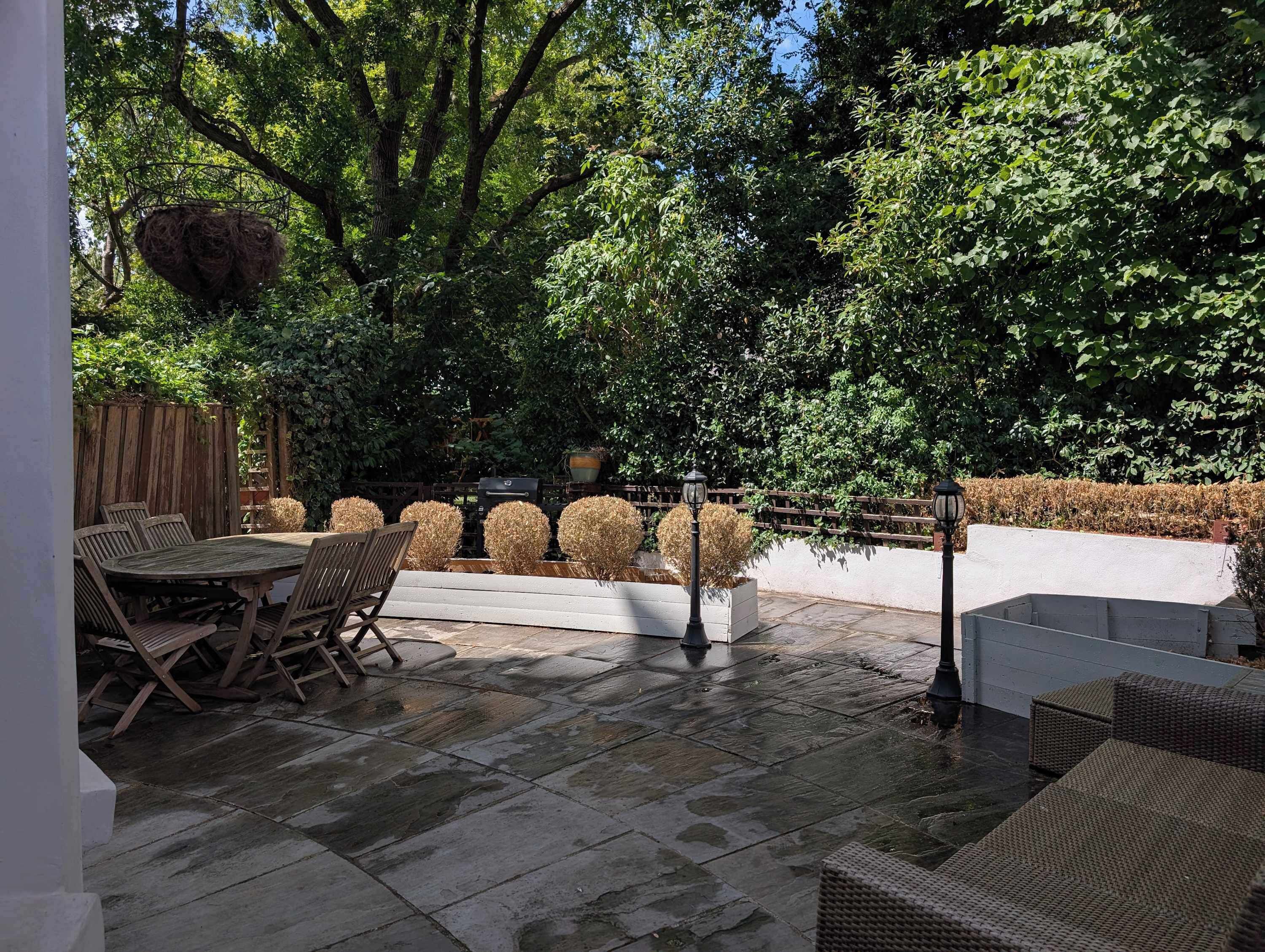 Eine Terrasse im Freien mit Steinboden, Holzmöbeln und einem Holzzaun.