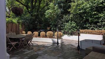Eine Terrasse im Freien mit Steinboden, Holzmöbeln und einem Holzzaun.