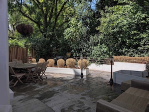 An outdoor patio with a stone floor, wooden furniture, and a wooden fence. - Stunning 2Bed flat with private patio (Greater London)