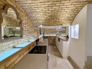 Una cocina estrecha con paredes de ladrillo visto, un banco empotrado y un lavabo.