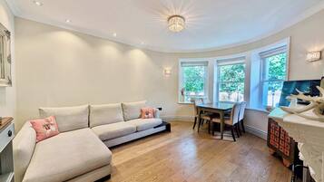 Ein modernes Wohnzimmer mit Sofa, Esstisch und Stühlen.