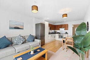 Um apartamento moderno com sala de estar, cozinha compacta e área de jantar.