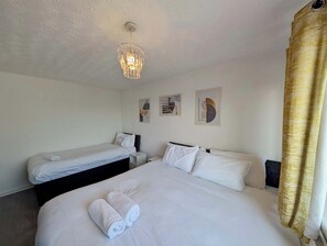 Ein Hotelzimmer mit zwei Betten, einer Chandelüstere, Bildern an den Wänden und einem Vorhang.
