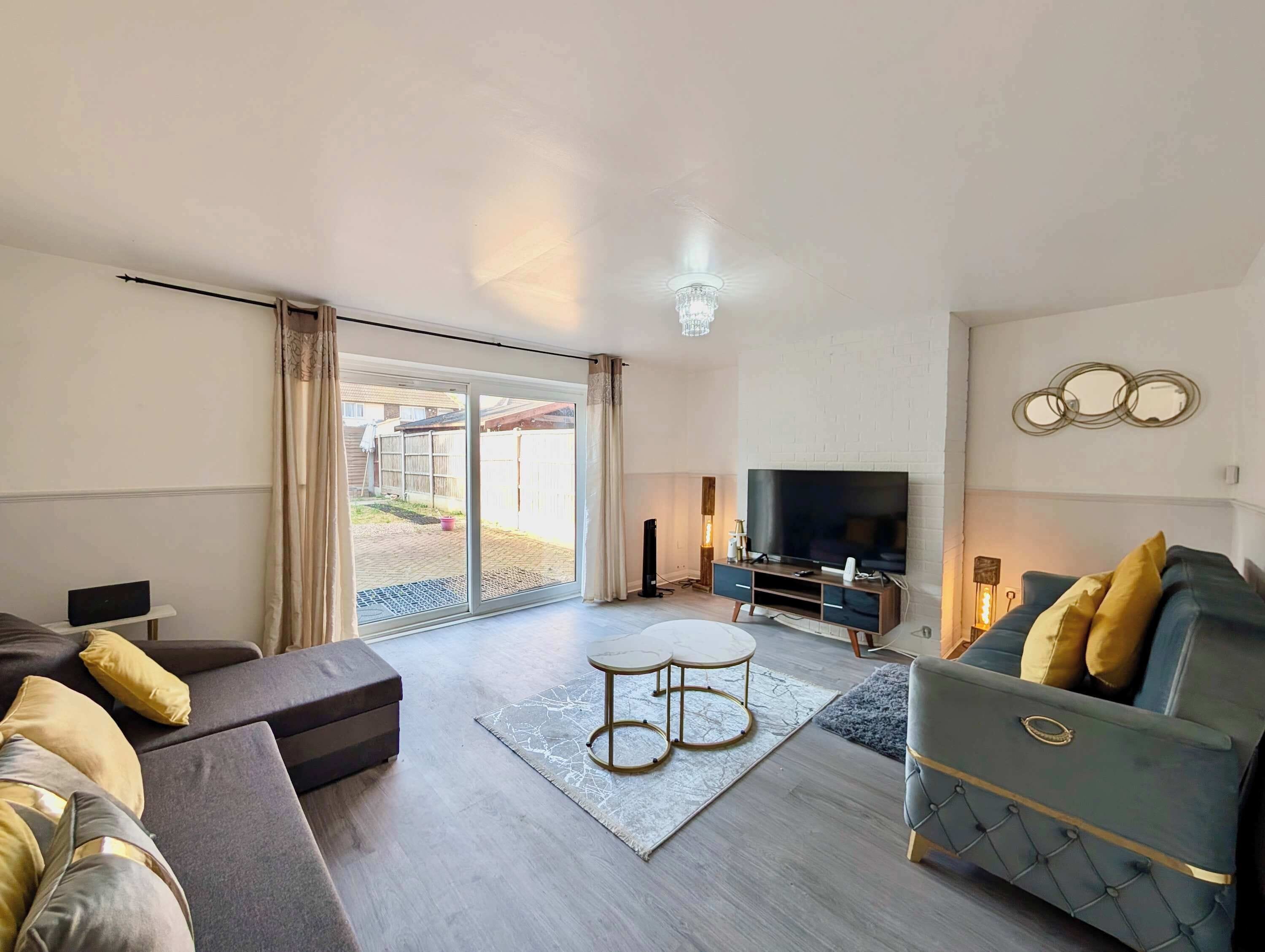 A modern living room with a sofa, a coffee table, a TV, and a sliding glass door leading to an outdoor area.