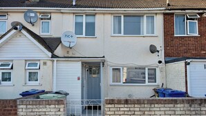 A residential building with a grey door, satellite dishes, and a visible garage door. - 3bed Tilbury house with free parking (Tilbury)