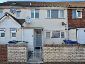 A residential building with a grey door, satellite dishes, and a visible garage door. - 3bed Tilbury house with free parking (Tilbury)