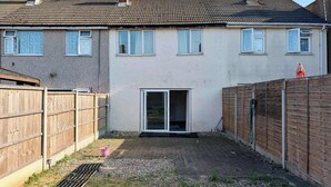 A residential property with a paved patio, a sliding glass door, and a wooden fence. - 3bed Tilbury house with free parking (Tilbury)