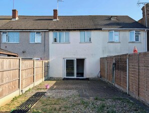 A residential property with a paved patio, a sliding glass door, and a wooden fence. - 3bed Tilbury house with free parking (Tilbury)