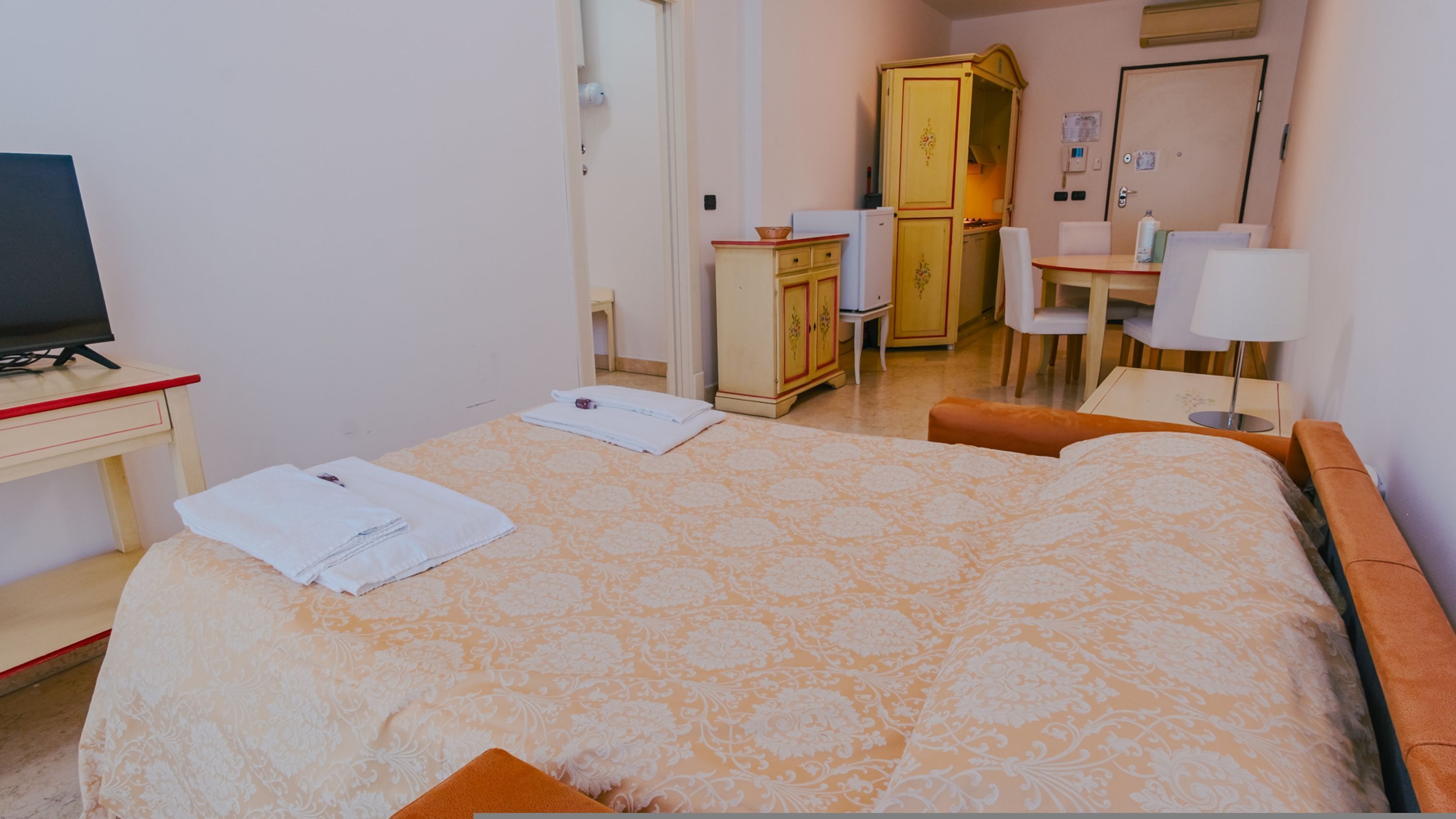 A hotel room with a bed, a desk, a chair, and a television.