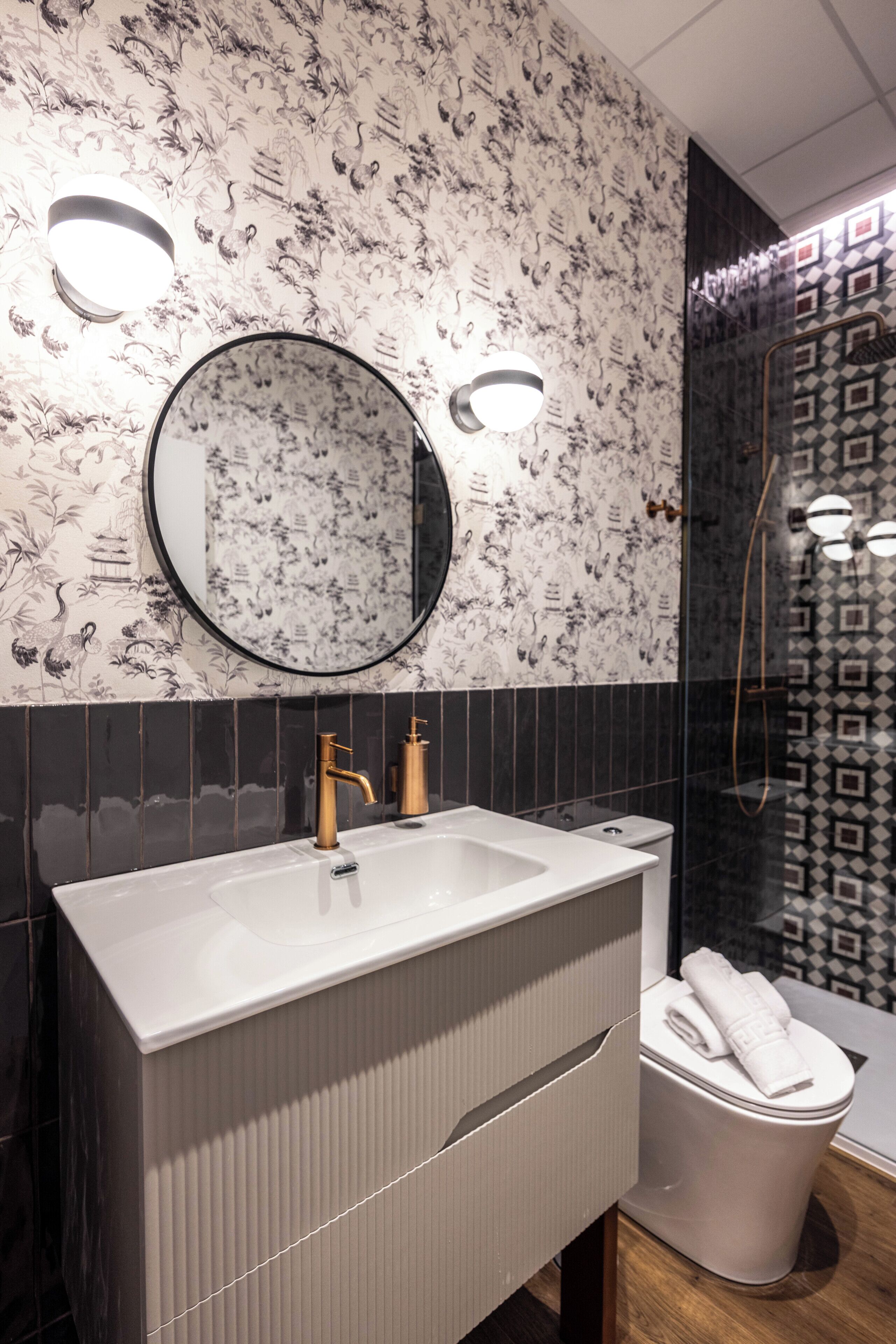 A bathroom with a large rectangular sink, a round mirror, and a toilet.