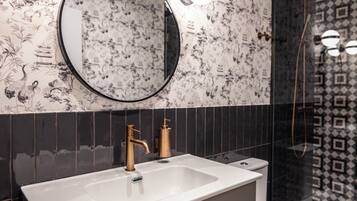 A bathroom with a large rectangular sink, a round mirror, and a toilet.