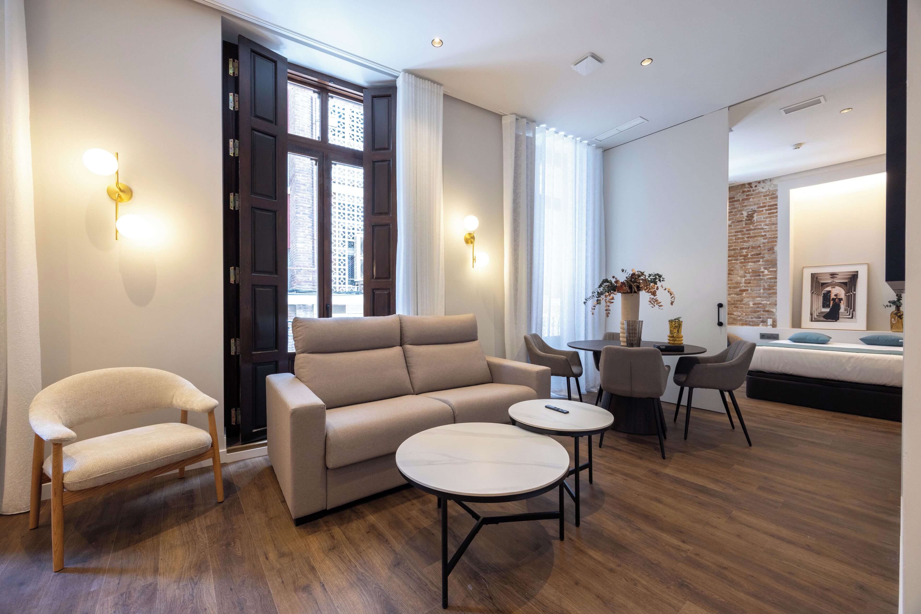 Une chambre d’hôtel moderne équipée d’un canapé, de fauteuils, d’une petite table et d’un coin repas avec des chaises.
