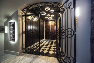 An interior with a checkered floor, a black metal gate, and a wall-mounted directory.