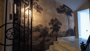 A staircase with a mural of a landscape, metal railings, and a wooden floor.