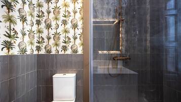 Ein Badezimmer mit Toilette, Dusche und einer Wand mit tropischem Wanddesign.