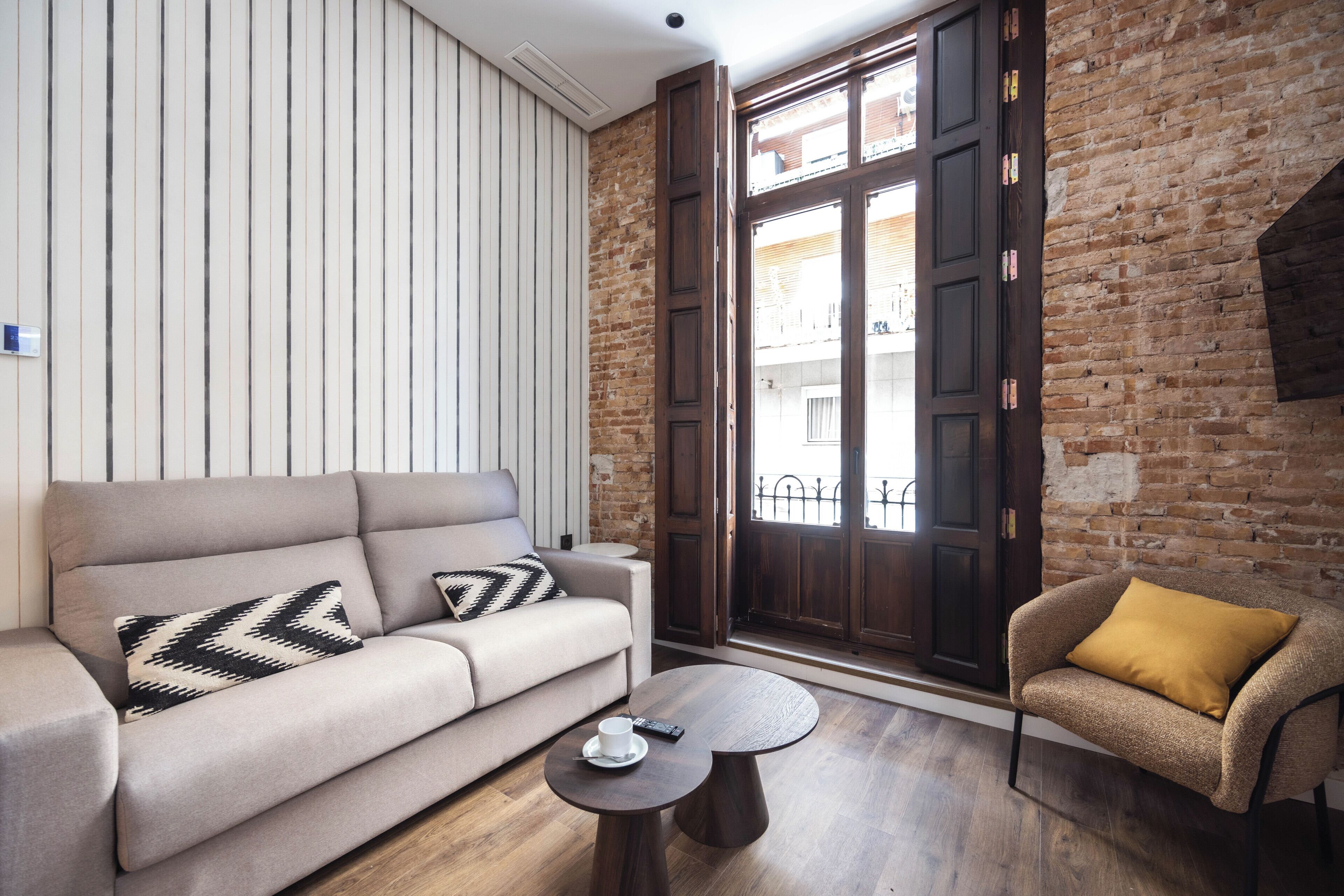 Una sala moderna con un sofá, una mesa de centro redonda y un sillón.