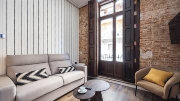 Una sala moderna con un sofá, una mesa de centro redonda y un sillón.