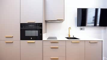 Una cucina moderna con forno a incasso, TV a parete e lavello con rubinetto dorato.