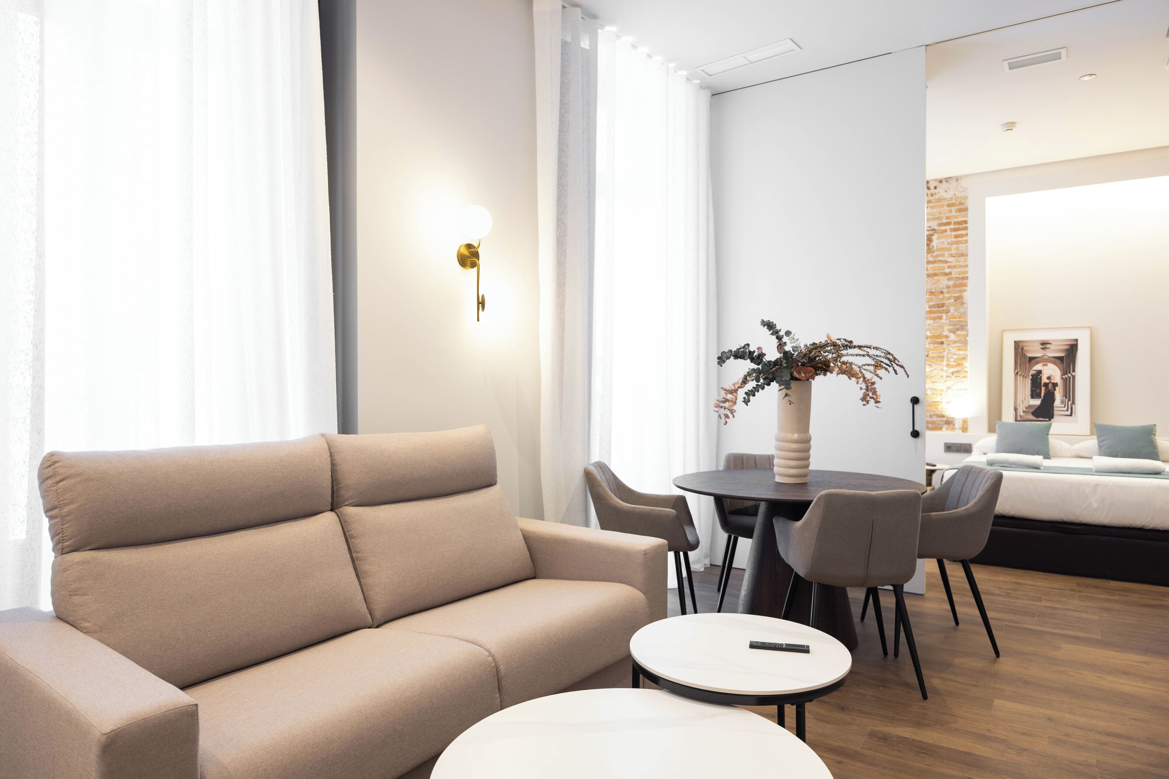 A modern hotel room with a sofa, a round dining table, and chairs.