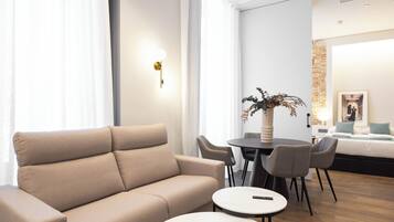 Et moderne hotelværelse med sofa, rundt spisebord og stole.
