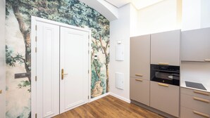 A modern kitchen with a built-in oven, grey cabinets, and a wall-mounted light switch.