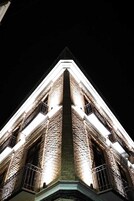 Un edificio alto con una sección angular destacada, iluminada durante la noche.