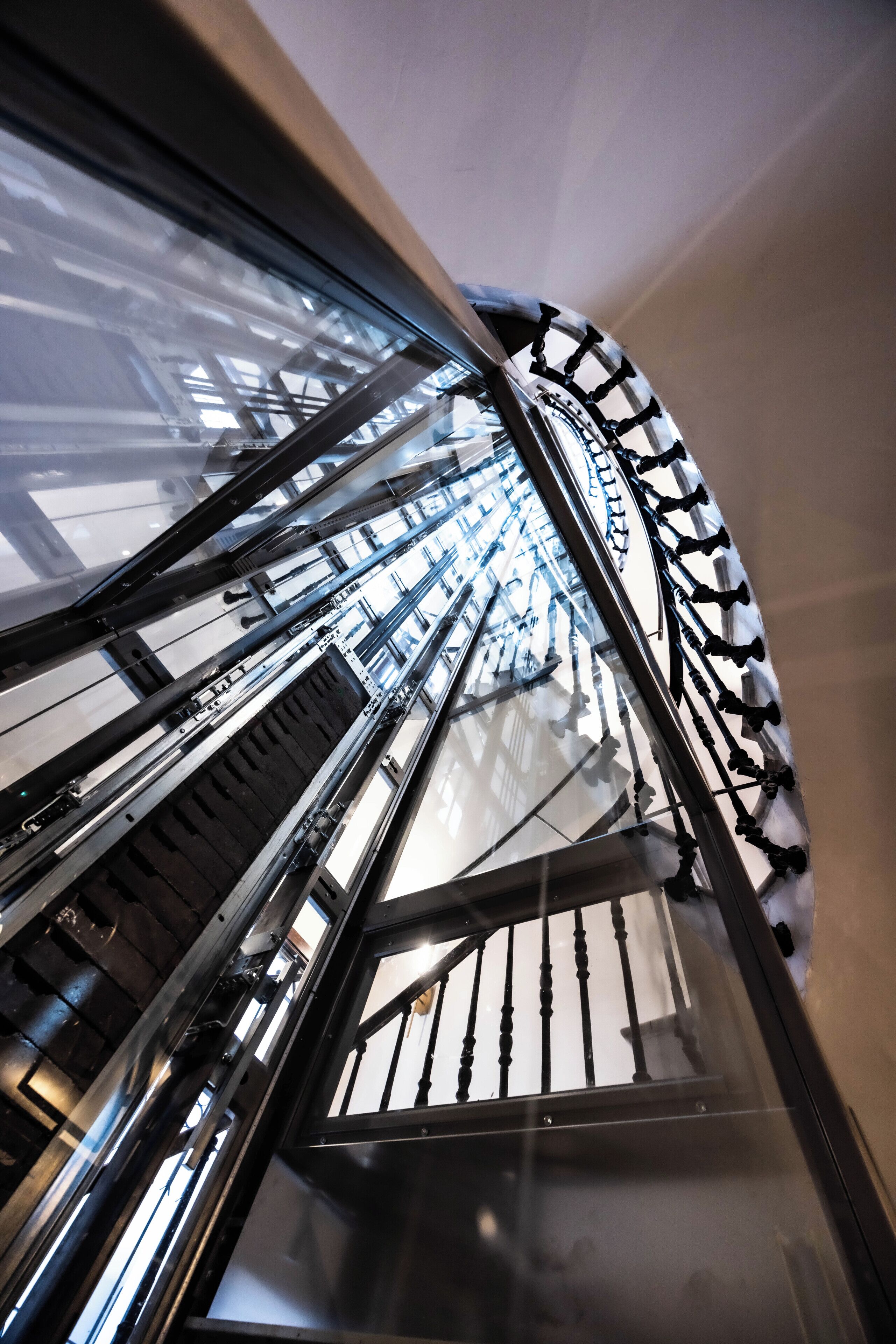 Una escalera de caracol con barandas de metal y paneles de vidrio.