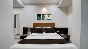 Ett modernt hotellrum med en stor säng, två sängbord, en sänggavel och tre konstverk som hänger på väggen.