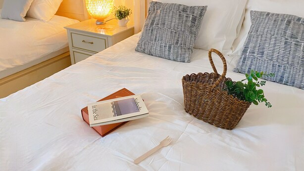 A hotel room with a neatly made bed, a bedside lamp, a basket with a plant, and a book titled 'Nobody in the Sea'. - House Gangnam - offers a modern, cozy space (Seoul)