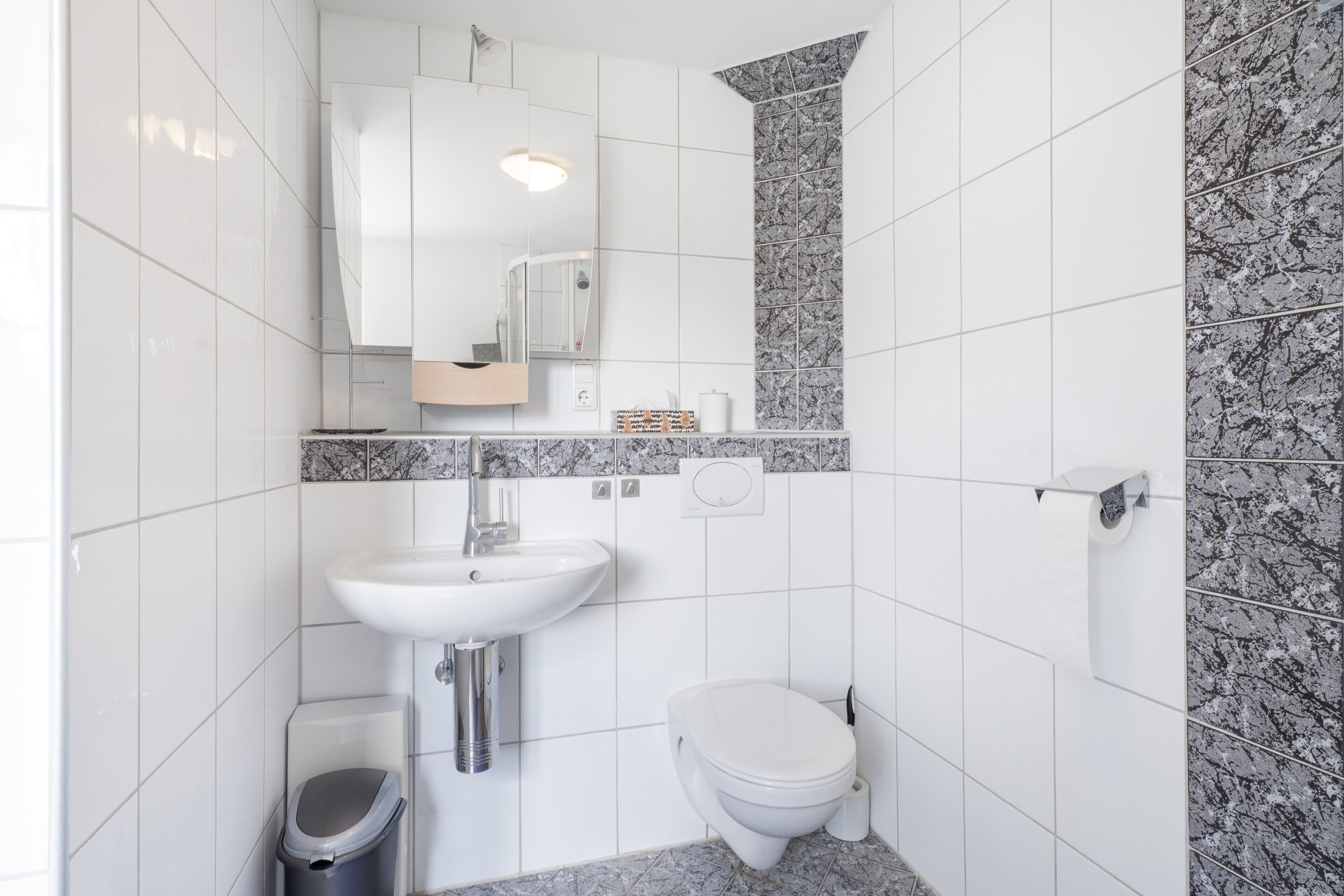 A bathroom with a white sink, a toilet, and a mirror.