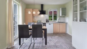 Een moderne keuken met een eethoek, voorzien van een vaatwasser, een koffiezetapparaat en een kast met glazen.