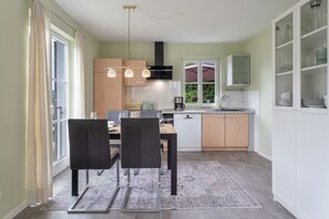 A modern kitchen with a dining area, featuring a dishwasher, a coffee maker, and a cabinet with glassware. - Wiesentflair Holiday Home with Panoramic Views in Muggendorf – 2 Bedrooms, 4 Guests (Wiesenttal)