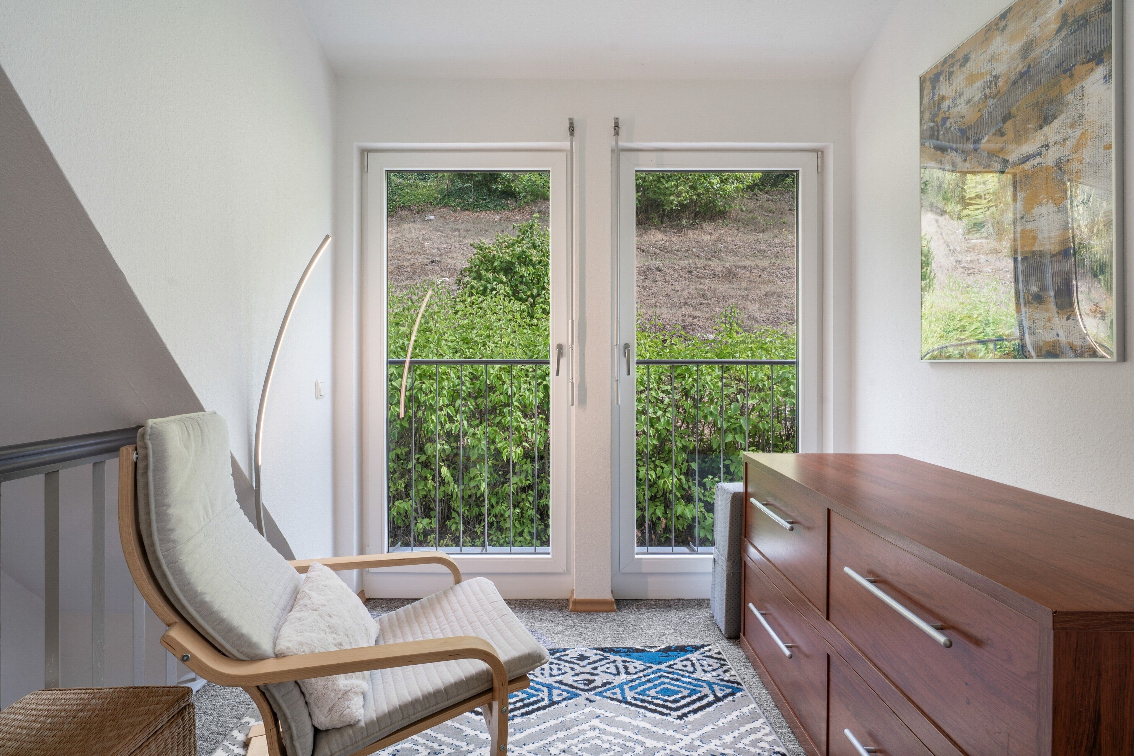 A room with a wooden chair, a dresser, and a patterned rug.