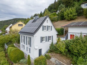 A residential building with solar panels, a white exterior, and a red door.