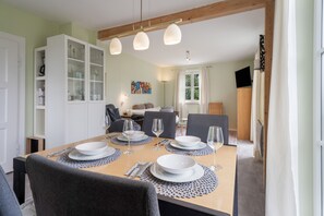 A dining area with a table set for four, chairs, and a cabinet with glass doors.