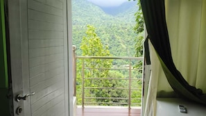 A balcony with a metal railing overlooking a lush green landscape.