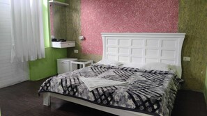 A bedroom with a bed, bedside tables, and a dresser.