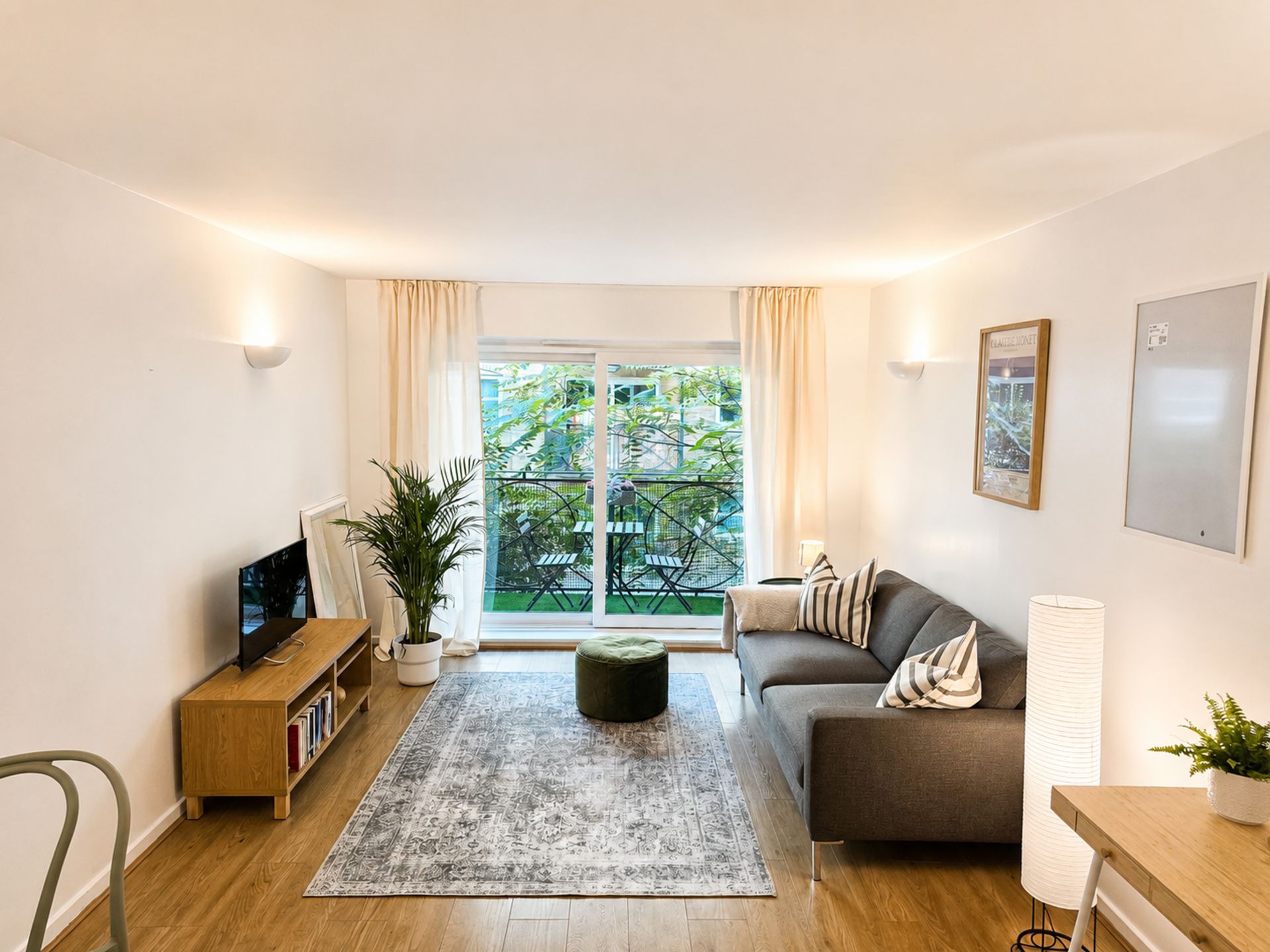 Uma sala de estar moderna com sofá, televisão e uma grande janela.