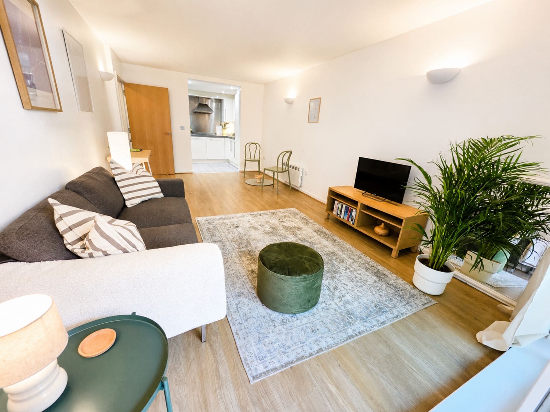 Una sala de estar con un sofá, una mesita de centro, un mueble para televisión y una planta en maceta.