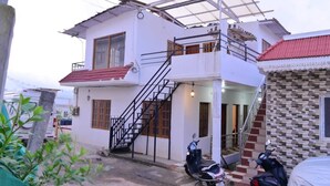 Una casa de dos pisos con un balcón, una escalera y un porche cubierto.