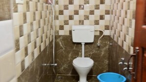 Un baño pequeño con un inodoro, un bidé y un balde azul.