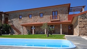 Un bâtiment en pierre avec une piscine devant.